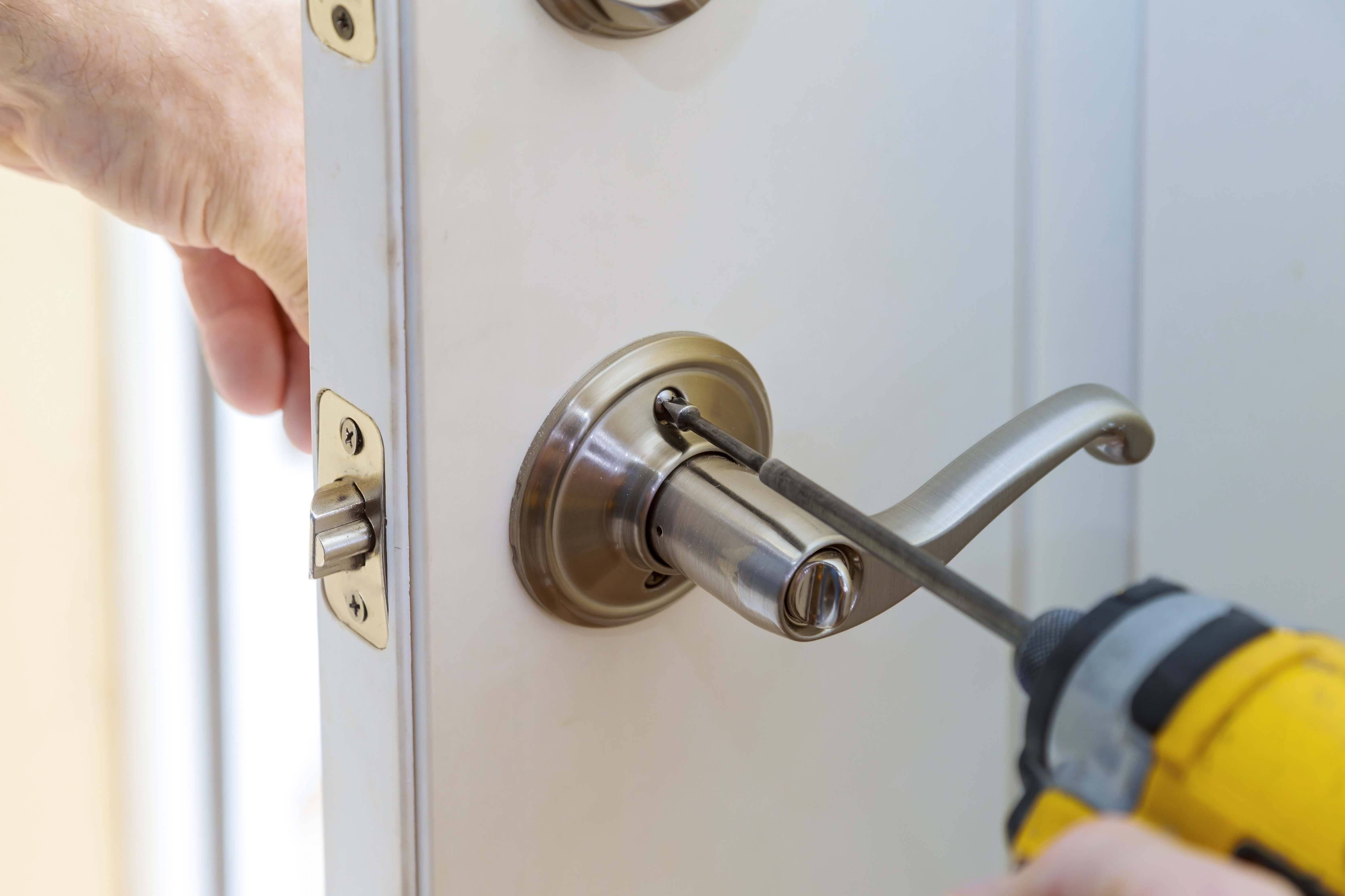 Locksmith installing a new lever handle and lock on a residential door